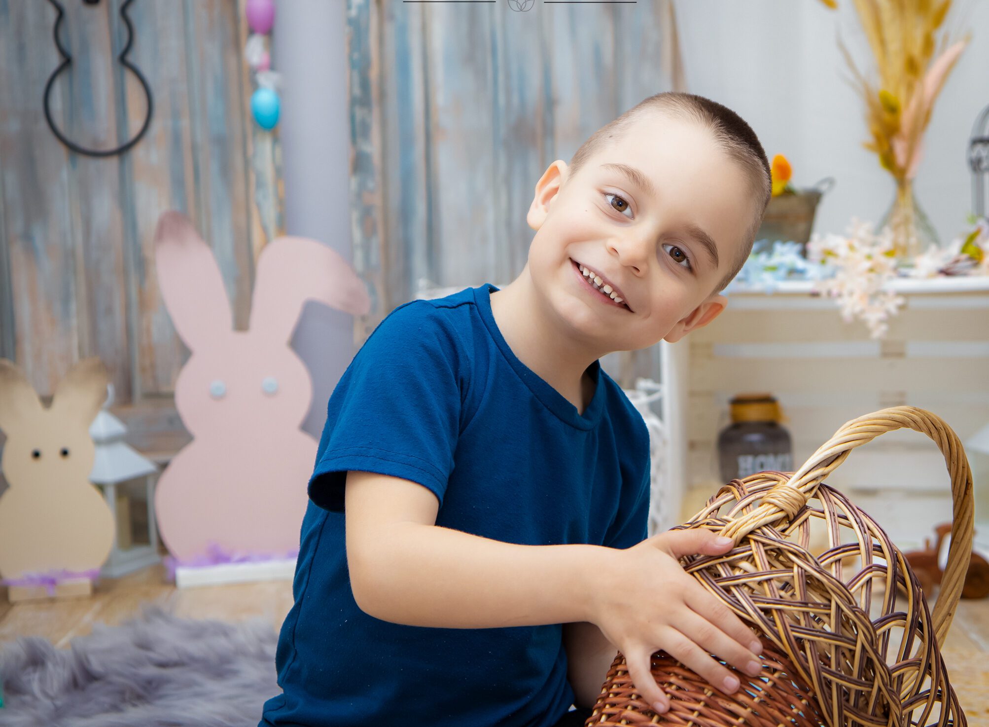 Gyermek portré húsvéti stúdiófotózáson, huncut mosollyal és egy csokikat kereső kosárral